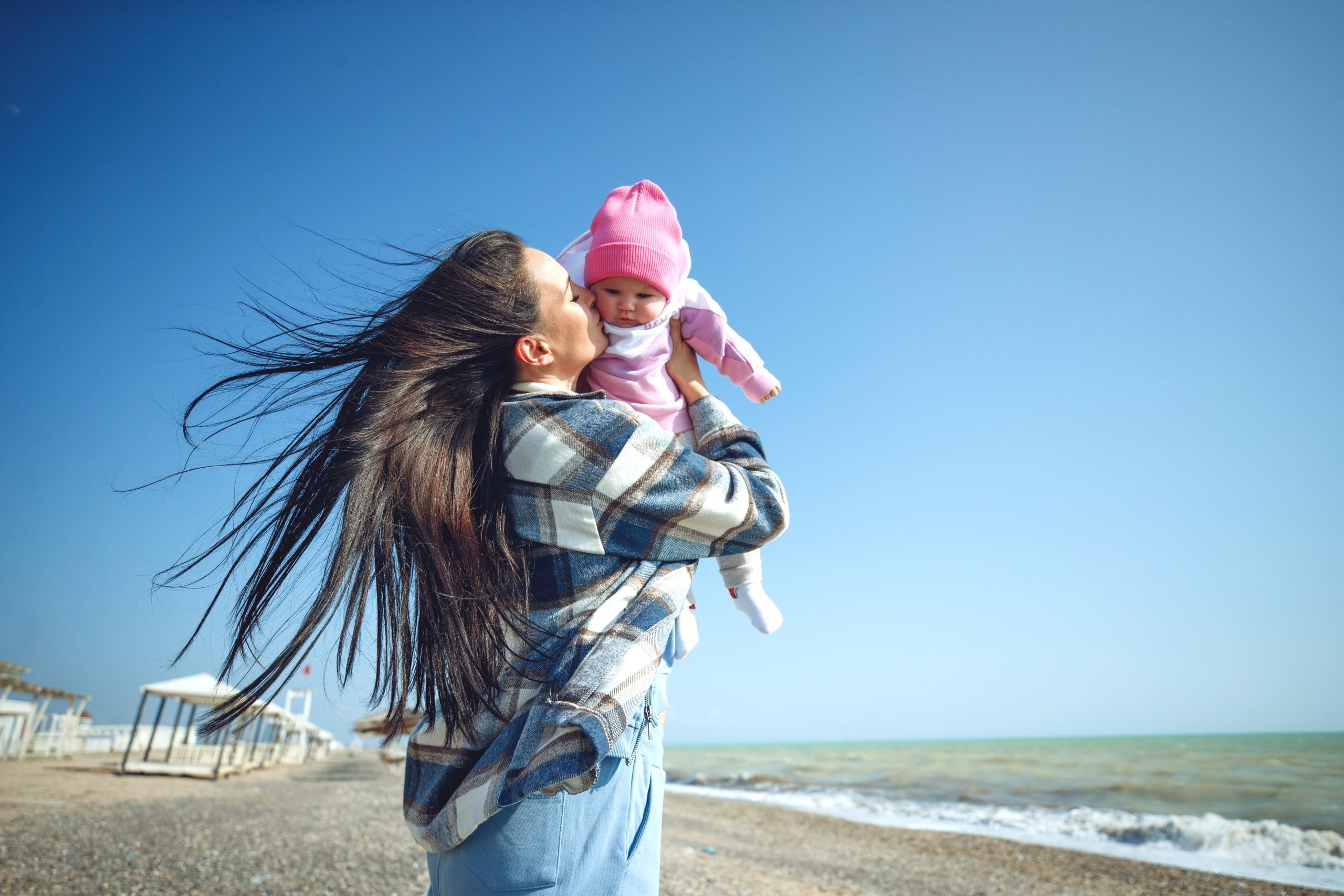 A woman with a child by the sea. Beautiful mother plays with her baby by the sea. High quality photo